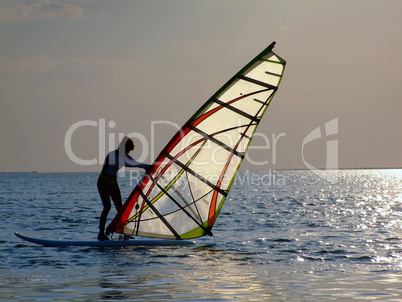 A women is learning windsurfing at the sunset