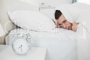 Annoyed man being awakened by an alarm clock