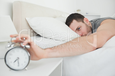Sleeping attractive man being awakened by an alarm clock