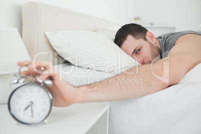 Attractive man being awakened by an alarm clock