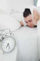 Portrait of an attractive man covering his ears while his alarm