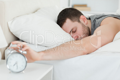 Sleeping man being awakened by an alarm clock