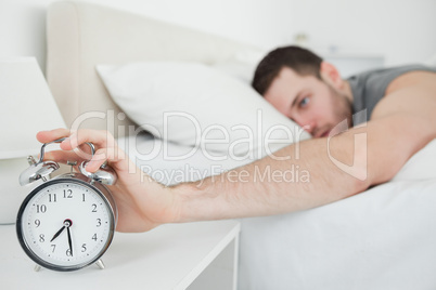 Young man being awakened by an alarm clock