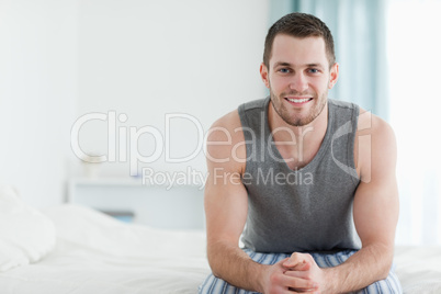 Smiling man sitting on his bed