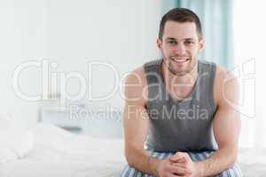 Smiling man sitting on his bed