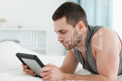 Young man using a tablet computer while lying on his belly