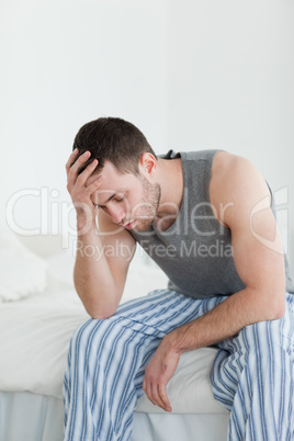 Portrait of an exhausted man sitting on his bed
