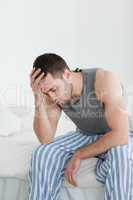 Portrait of an exhausted man sitting on his bed