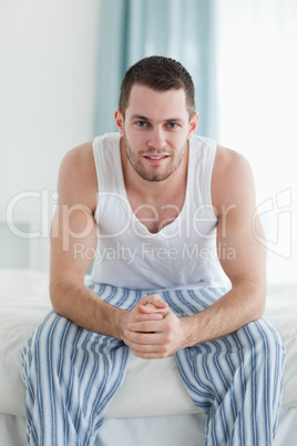 Portrait of a smiling man sitting on his bed