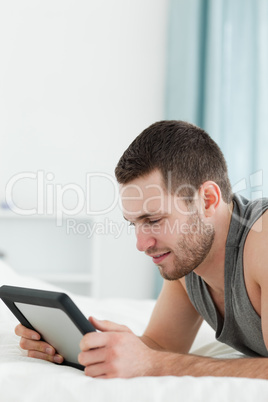 Portrait of a young man using a tablet computer while lying on h