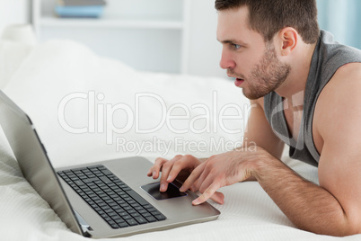 Man using a laptop while lying on his belly