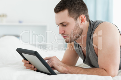 Handsome man using a tablet computer while lying on his belly