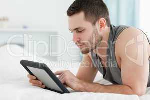 Handsome man using a tablet computer while lying on his belly