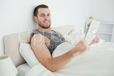 Smiling young man reading a newspaper