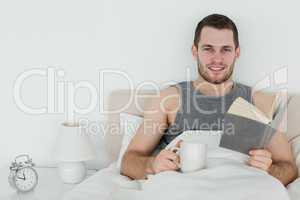 Man reading a novel while holding a cup of tea