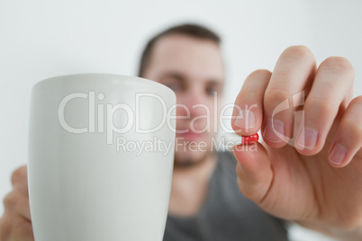 Man showing a pill and and a mug