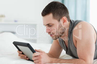 Man using a tablet computer while lying on his belly