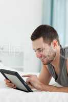 Portrait of a smiling man using a tablet computer while lying on