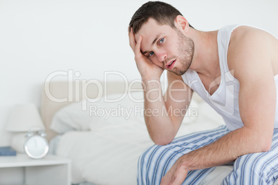Sick man sitting on his bed