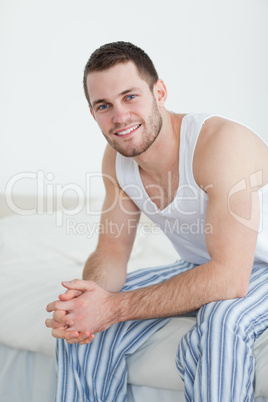 Portrait of a smiling young man sitting on his bed