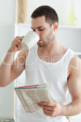 Portrait of a young man drinking tea while reading the news