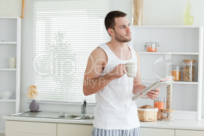 Good looking man drinking coffee while reading the news