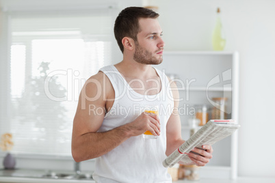 Young man drinking orange juice while reading the news