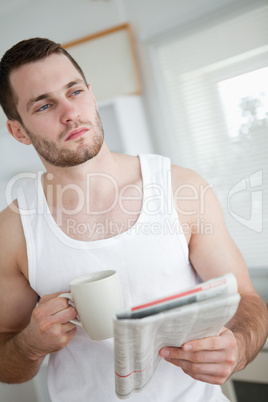 Portrait of a serious man drinking orange juice while reading th