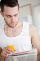 Portrait of a beautiful man drinking orange juice while reading