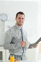 Portrait of a smiling businessman reading the news while having