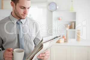 Businessman reading a newspaper while drinking tea
