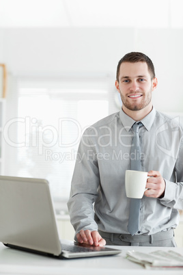 Portrait of a businessman using a notebook while drinking coffee