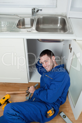 Portrait of a smiling repairman fixing a sink