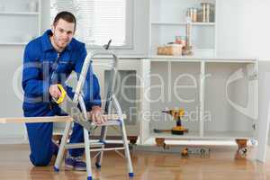 Smiling handyman cutting a wooden board