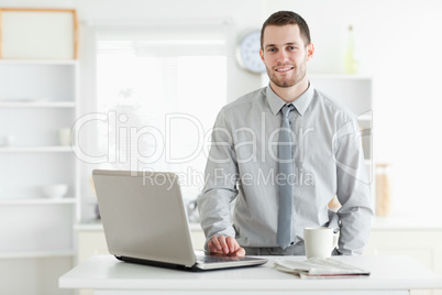 Businessman using a laptop while drinking tea