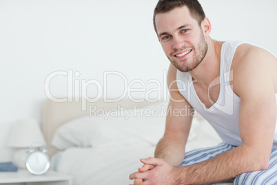 Smiling young man sitting on his bed