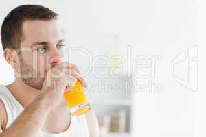 Portrait of a delighted man drinking orange juice