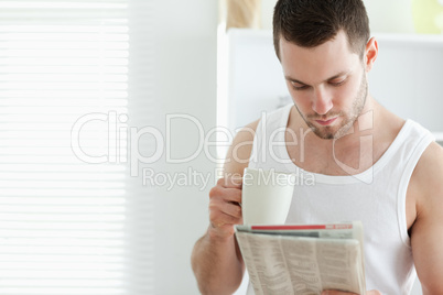 Smiling man drinking coffee while reading the news