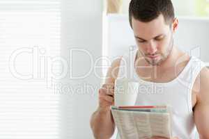 Smiling man drinking coffee while reading the news