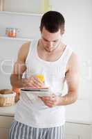 Portrait of a man reading the news while drinking orange juice