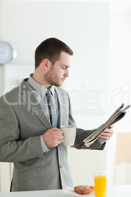 Portrait of a businessman having breakfast while reading the new