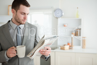 Businessman drinking coffee while reading the news