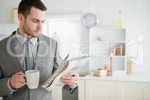 Businessman drinking coffee while reading the news