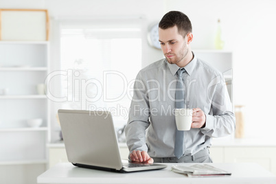 Businessman using a laptop while drinking coffee