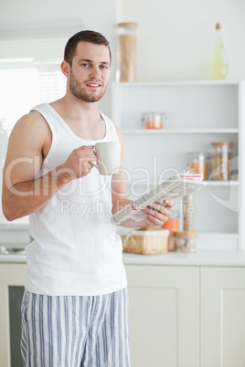 Portrait of a sports man drinking coffee while reading the news