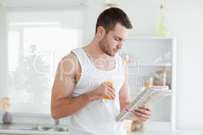 Man drinking orange juice while reading the news