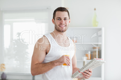 Handsome man drinking orange juice while reading the news