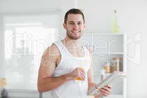 Handsome man drinking orange juice while reading the news