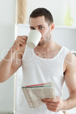 Portrait of a handsome man drinking tea while reading the news