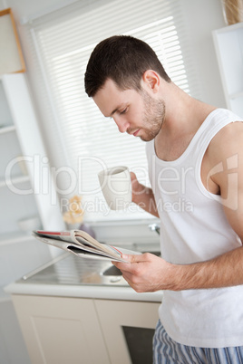 Portrait of a good looking man drinking coffee while reading the